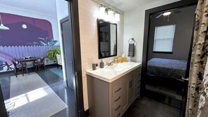 A modern bathroom with a large mirror, a sink, and a shower area. - Stay Roanoke | Luxe rooftop retreat in downtown (Roanoke)