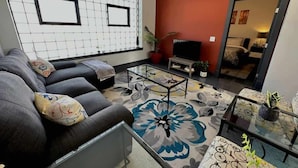 A modern living room with a sofa, coffee table, and a patterned rug. - Stay Roanoke | Luxe rooftop retreat in downtown (Roanoke)