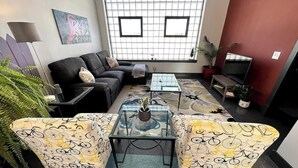 A living room with a sofa, two armchairs, a coffee table, and a TV. - Stay Roanoke | Luxe rooftop retreat in downtown (Roanoke)