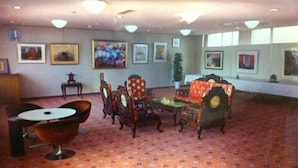 A spacious lobby with a patterned carpet, a round table, a sofa, and several chairs. - Kawanoe Business Hotel (Shikokuchuo)