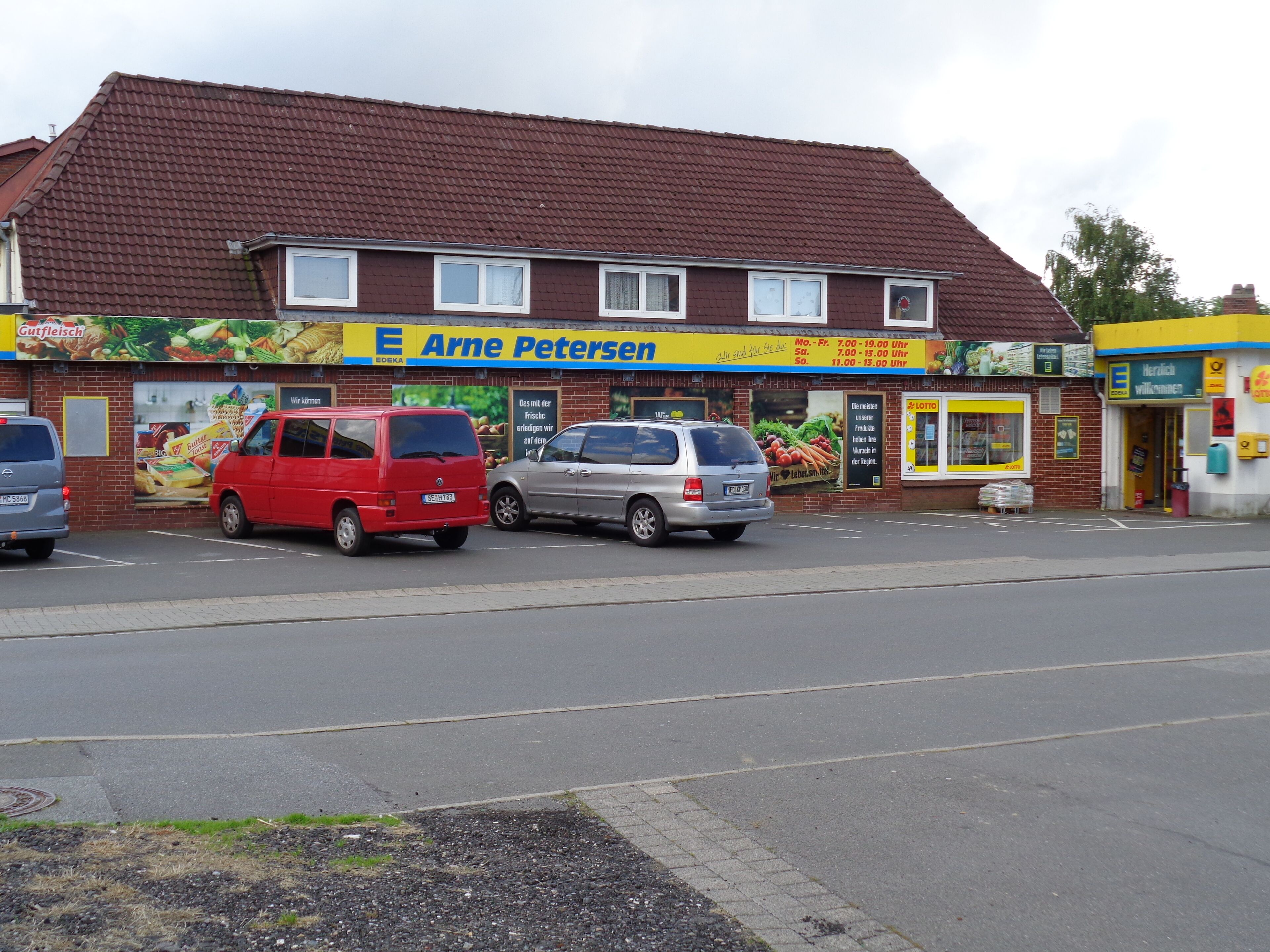 A two-story building with a red roof and a sign for 'Arne Petersen' on the ground floor.