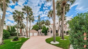 Zona residencial con un camino pavimentado, palmeras y casas con puertas de garaje.