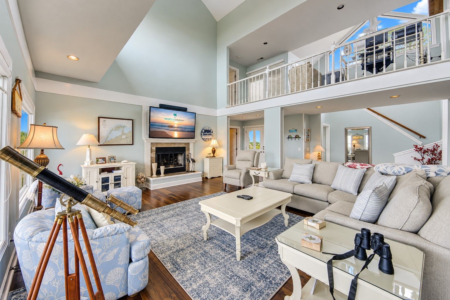 A spacious living room with a fireplace, comfortable seating, a telescope, and a balcony with a view.
