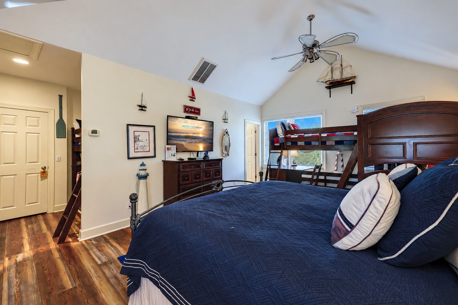 Ein Schlafzimmer mit Etagenbett, Fernseher, Schreibtisch mit Stuhl und Fenster mit Blick.