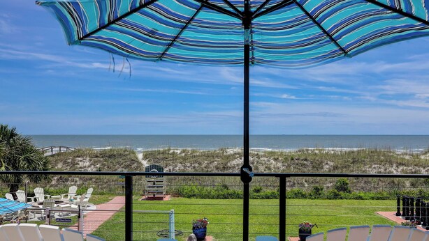 A poolside view with a clear view of the ocean, a grassy area, and a fenced deck with lounge chairs. - 33 Sandpiper- Oceanfront, The NEW Daisy. LARGE Private Pool & Fire Pit (Hilton Head Island)