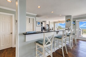 A kitchen with a bar area, white cabinetry, and a view to the outside.