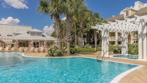 A pool area with clear blue water, surrounded by palm trees and lounge chairs. - Studio Unit ~ Bayside Gated Resort ~ Kitchenette (Miramar Beach)