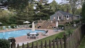 Ein Garten mit Swimmingpool, Liegestühlen und einer Holzterrasse.
