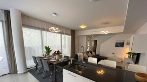 Una cocina moderna con una isla central, comedor con sillas y vistas al exterior a través de amplios ventanales.