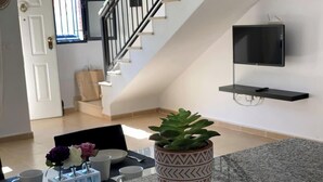 Ein modernes Wohnzimmer mit Treppe, einem Wand-Fernseher und einem Blumentopf auf der Arbeitsplatte.