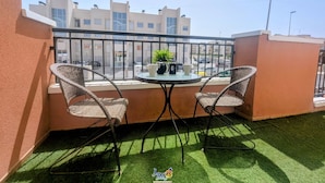 Ein Balkon mit zwei Korbstühlen, einem kleinen Tisch und einem Blumentopf.