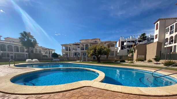 A swimming pool surrounded by buildings with a clear blue sky.