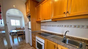 A kitchen with wooden cabinets, a granite countertop, a stainless steel sink, and a built-in oven.