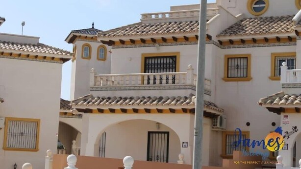 Un bâtiment de style espagnol traditionnel, doté de nombreux balcons, de murs blancs et de bordures jaunes.