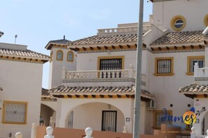 Ein Gebäude im traditionellen spanischen Stil mit mehreren Balkonen, weißen Wänden und gelbem Zierstreifen.