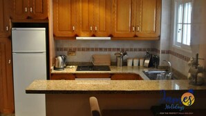 Une cuisine avec des meubles de rangement en bois, une cuisinière encastrée et un réfrigérateur.