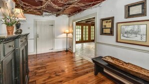 A hallway with wooden flooring, a bench, framed pictures, and a lamp. - Stone Creek Farm (Easton)