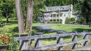A large, two-story house with a wrap-around porch and a flagpole. - Stone Creek Farm (Easton)