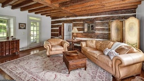 A rustic living room with leather sofas, a wooden coffee table, and a patterned rug. - Stone Creek Farm (Easton)