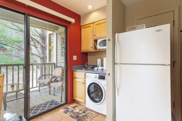 A compact kitchen with a washing machine, a microwave, and a refrigerator.