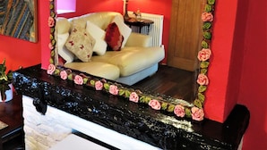 A room with a mirror, a clock, a sofa, and a lamp.