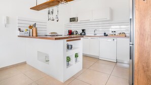 A modern kitchen with white cabinetry, a wooden island, and a stainless steel refrigerator. - Villa Nirvana - Alfresco Villas - Breathtaking view (Sivota)