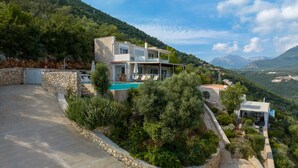 A hillside villa with a swimming pool, stone walls, and lush greenery. - Villa Nirvana - Alfresco Villas - Breathtaking view (Sivota)