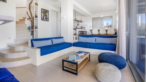 A modern living room with a staircase, a sofa set, a coffee table, and a view of the kitchen.