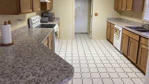 Una cocina compacta con armarios de madera, un microondas, una estufa y un fregadero.