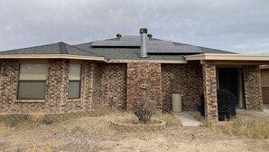 Una casa con fachada de ladrillo, una chimenea y paneles solares en el tejado.