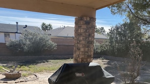 Una parrilla Weber con un tiro, sobre un patio de concreto con un pilar de ladrillo.