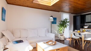 A modern living room with a white sofa, a wooden coffee table, a dining area with a white table and chairs, and a potted plant. - 4 Avocet Quay , Emsworth  - sleeps 4 guests  in 2 bedrooms (Emsworth)