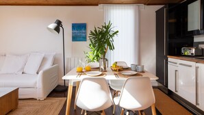 A modern kitchen with white cabinets, a dining table with chairs, a potted plant, and a white sofa in a bright room with wooden ceiling beams. - 4 Avocet Quay , Emsworth  - sleeps 4 guests  in 2 bedrooms (Emsworth)