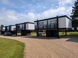 A modern building with a flat roof, large windows, and a balcony.