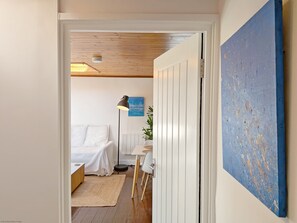 Une chambre à coucher avec un lit, une table de chevet, une lampe et une vue sur une autre pièce.
