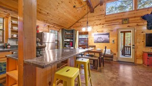 L’intérieur d’un chalet en bois comprend une cuisine, un coin repas et un bar.