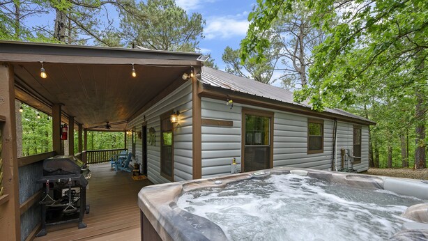 Une cabane dotée d’un bain à remous, d’un barbecue et d’une terrasse couverte.