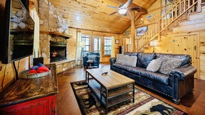 L’intérieur chaleureux d’un chalet en bois comprend une cheminée, un canapé en cuir, une table basse en bois et un escalier.