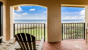 A balcony with a view of the ocean and a grassy area.