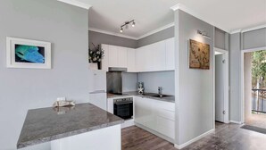 Een moderne keuken met witte kasten, een marmeren aanrechtblad en een inbouwoven.
