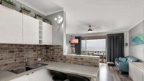 A modern kitchen with a built-in sink, bar stools, and a brick backsplash.