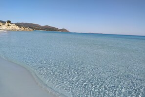 A clear beach with calm water and rocky hills in the background. - Villasimius-Gracious and bright townhouse, garden and veranda.WiFi free (Villasimius)