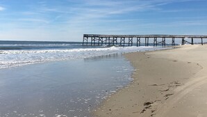 Ein Strand mit einem Steg, der sich ins Meer erstreckt.