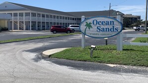 Schild für Ocean Sands, eine private Wohnanlage, mit einem Gebäude im Hintergrund.