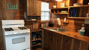Una cocina compacta con armarios de madera, una estufa blanca y un ventanal.