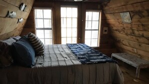 Un dormitorio acogedor tipo cabaña con cama, almohadas y un banco.