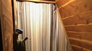Un baño pequeño con paneles de madera, un lavamanos, un perchero para toallas y una cortina de ducha.