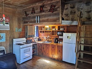 L’intérieur d’un chalet rustique comprend une cuisine équipée de meubles en bois, d’une cuisinière et d’un réfrigérateur.