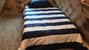 Una cama individual en una habitación con paredes de madera y techo inclinado.