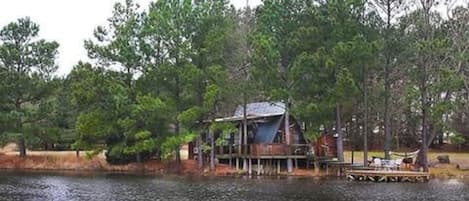 A cabin by a lake surrounded by trees.
